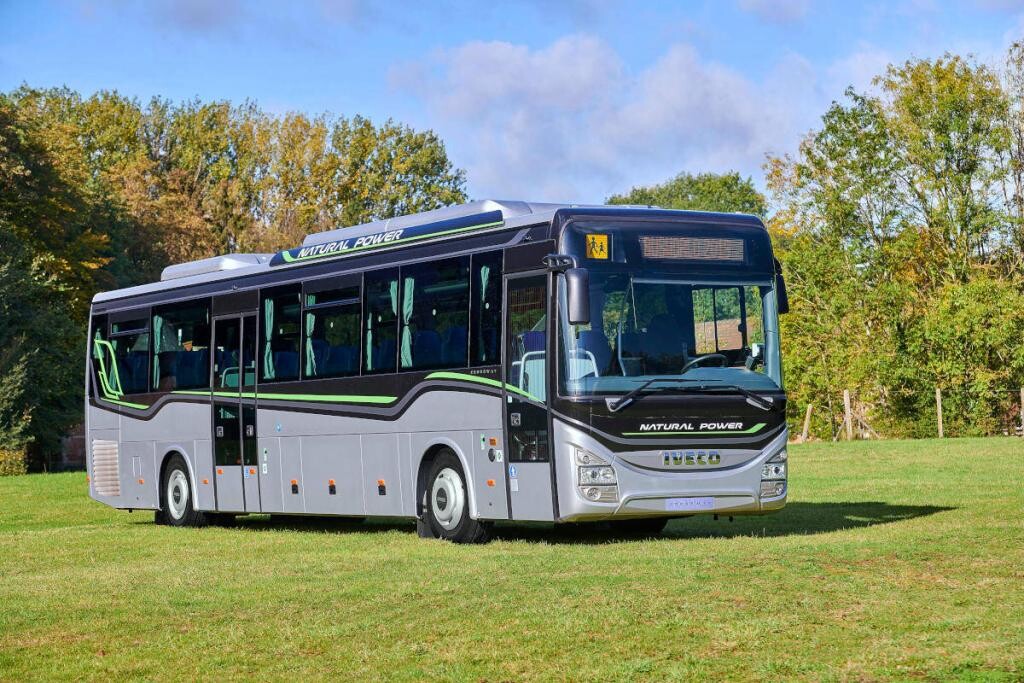 Iveco Bus Crossway CNG in Silber mit grünen und grauen Streifen steht auf einer grünen Wiese.
